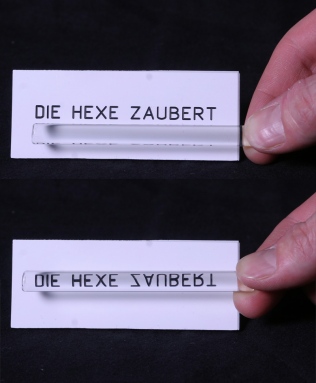 When you hold a see-through glass tube in front of a particular sign, only one word, “Zaubert”, is turned upside down. Why?